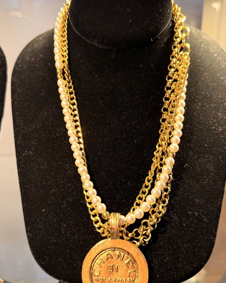 A gold chain and pearl necklace with a coin pendant