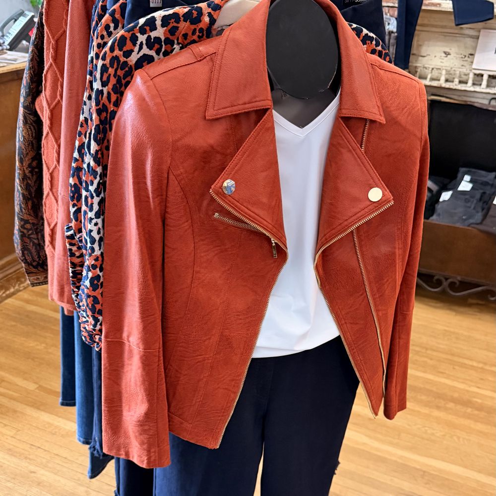 A rust moto jacket over a white tee on the women's floor
