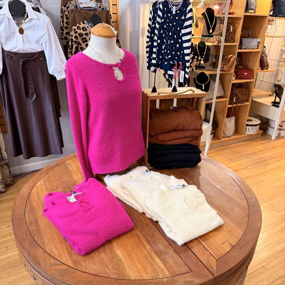A hot pink brushed knit with folded sweaters on the front table